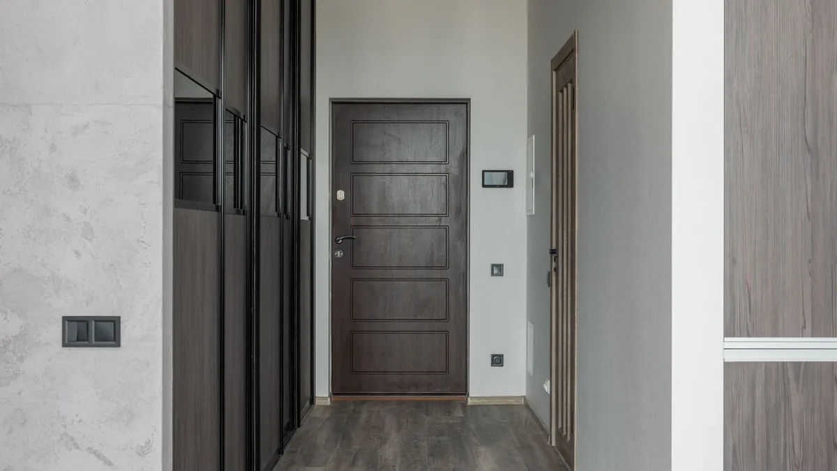 Wooden door meeting a parquet floor in a bright hallway, where cold air slips through the gap