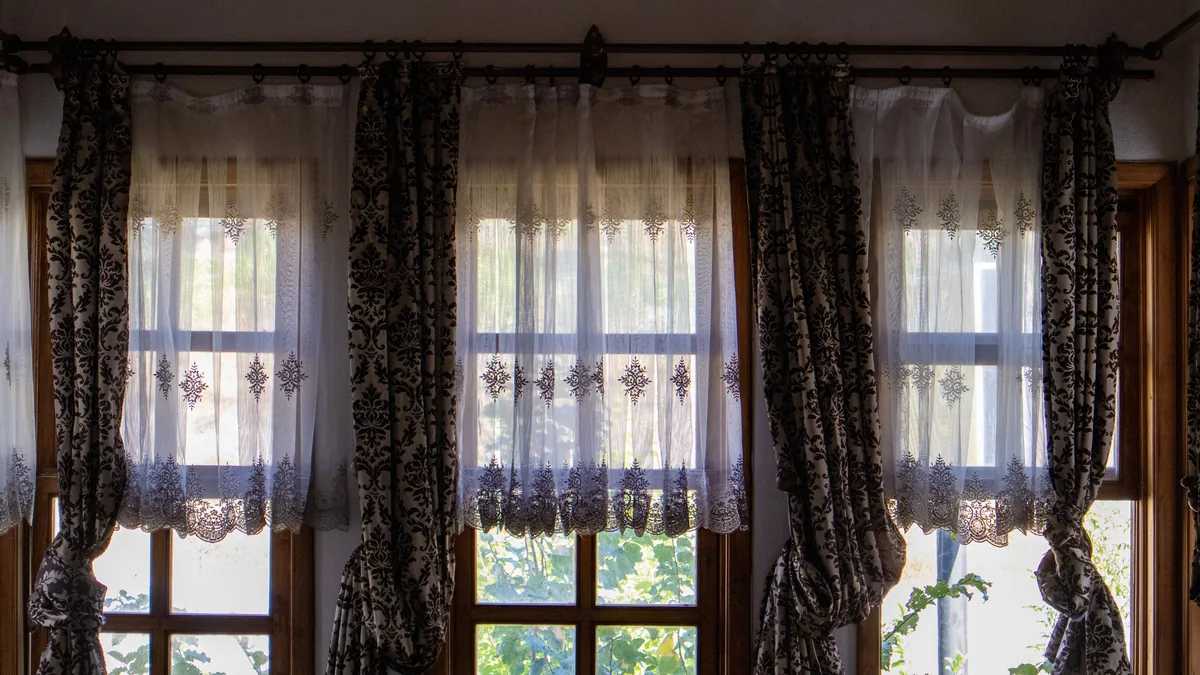 Sunlit room with elegant traditional curtains hanging over a large window