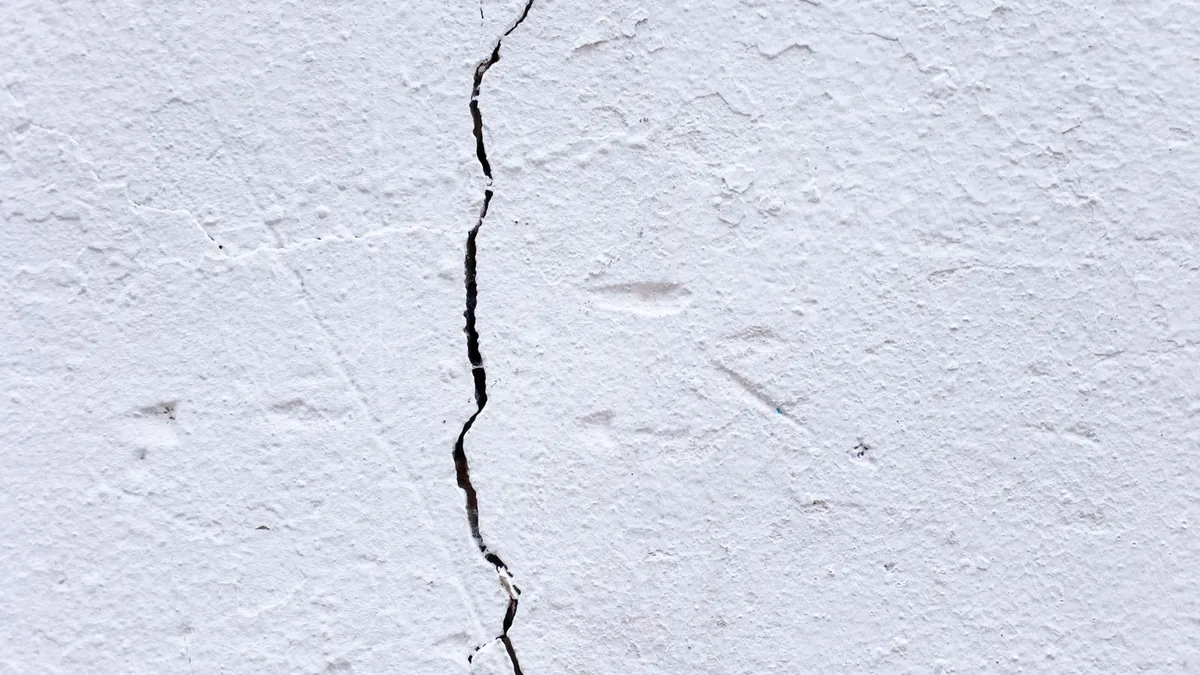 Cracked plaster wall surface with a long thin crack running across it