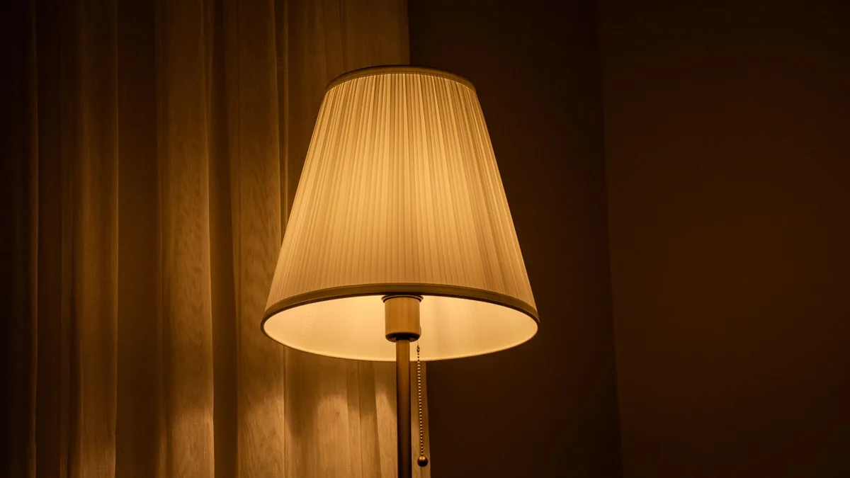 A softly glowing table lamp on a side table in a warm living room at night