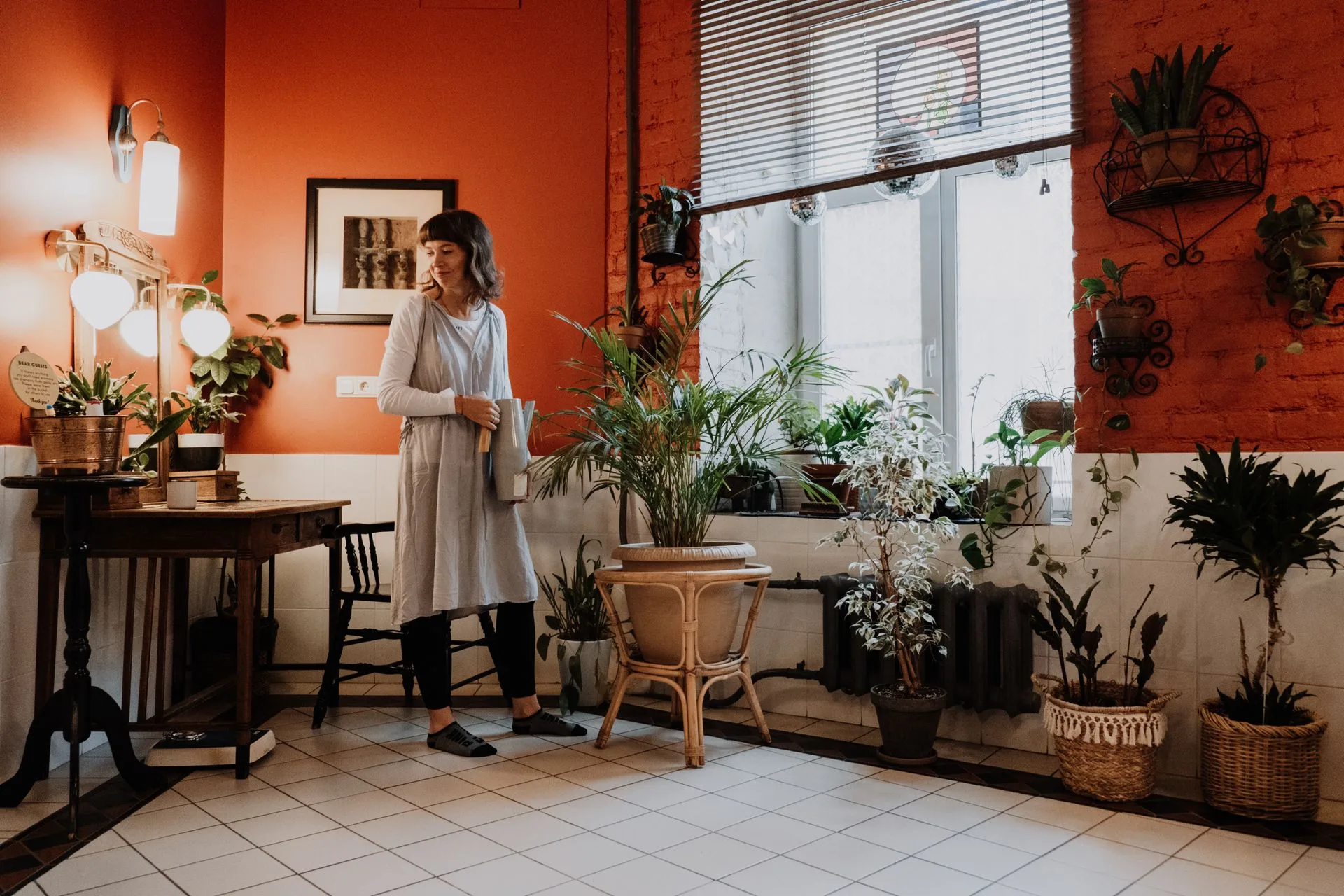 Living room styled with potted houseplants on a plant stand and a shelf near a window