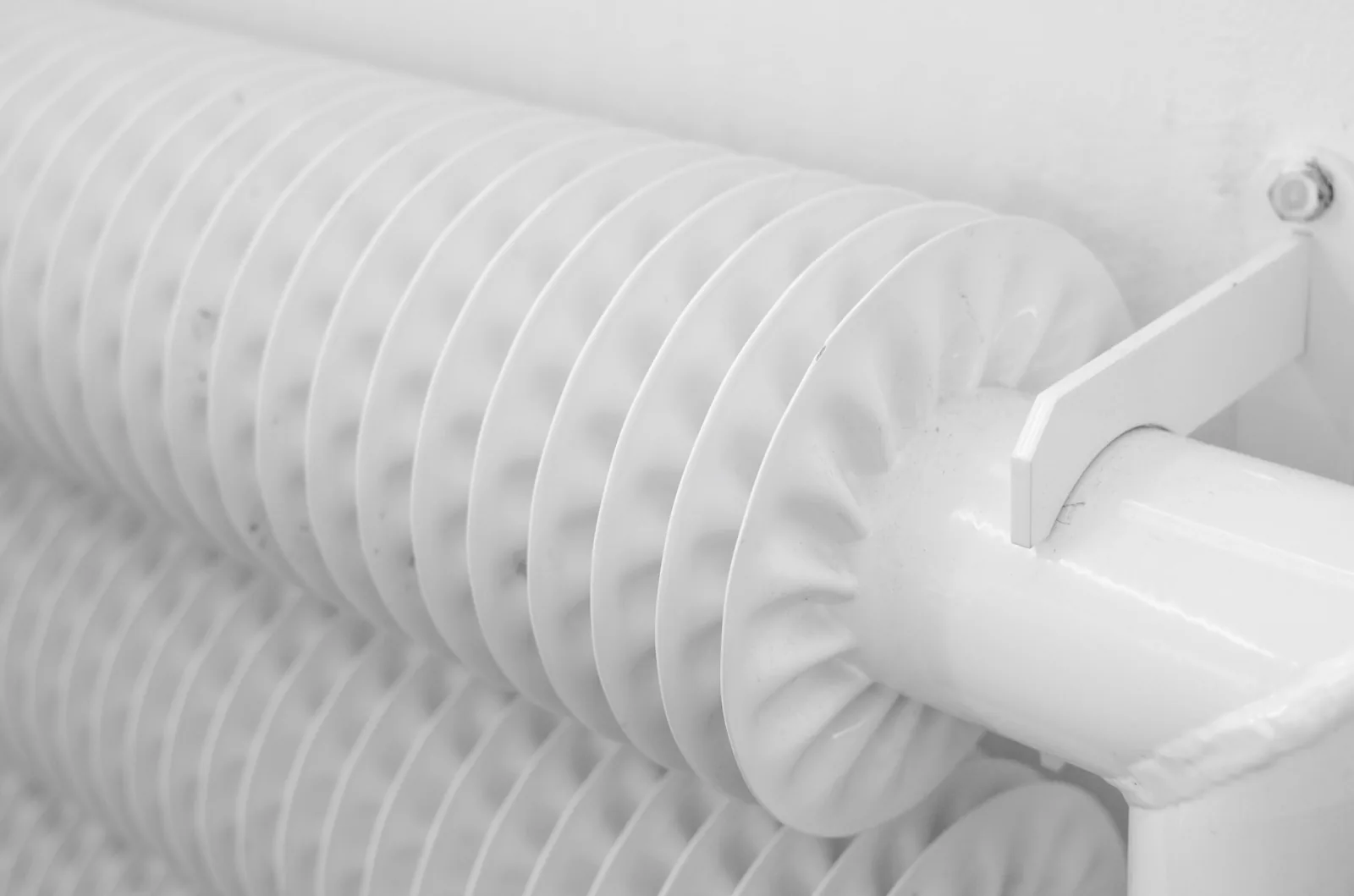 White radiator mounted on a wall in a bright room at home